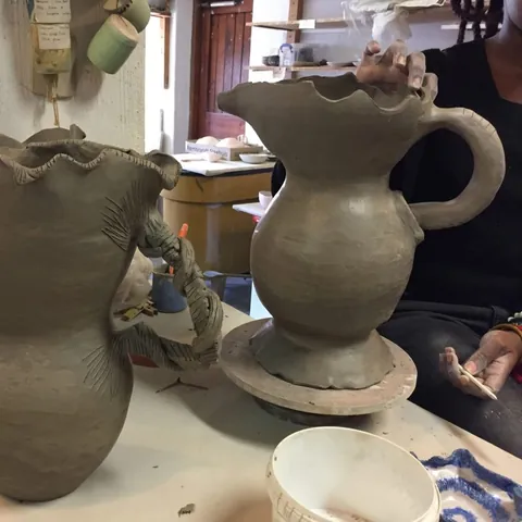 Tall hand-built clay vessels with frilled rims in a studio