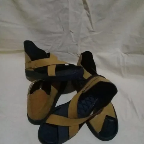A pair of tan leather sandals with black cross straps
