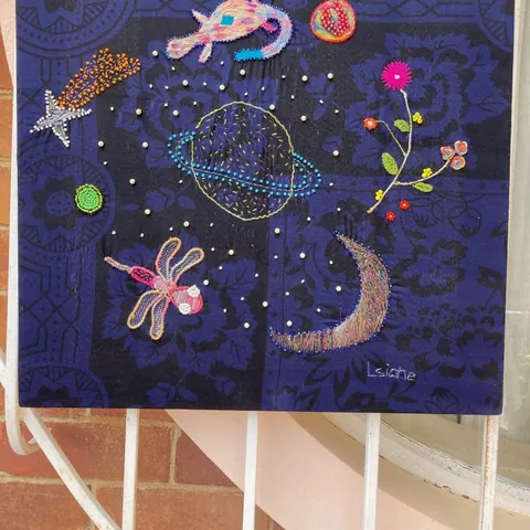A dark blue panel embroidered with a ringed planet, a moon and stars