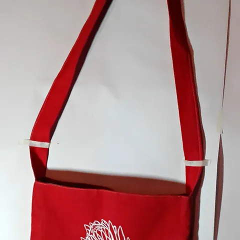 A red shoulder bag printed with a white protea