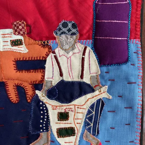 An appliqué panel of a man in a hat and waistcoat on patchwork cloth